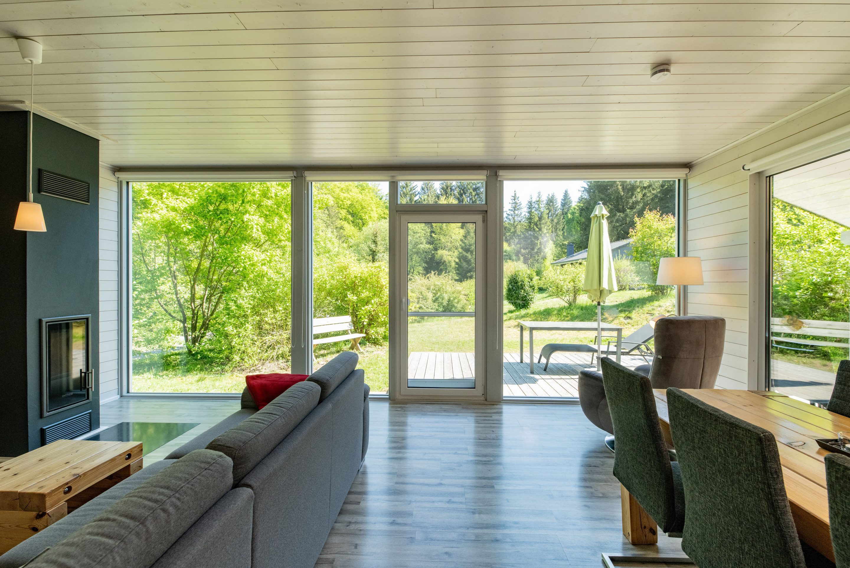 Lichtdurchfluteter Wohnbereich mit Panoramafenstern und Kamin im Ferienhaus bis vier Personen.